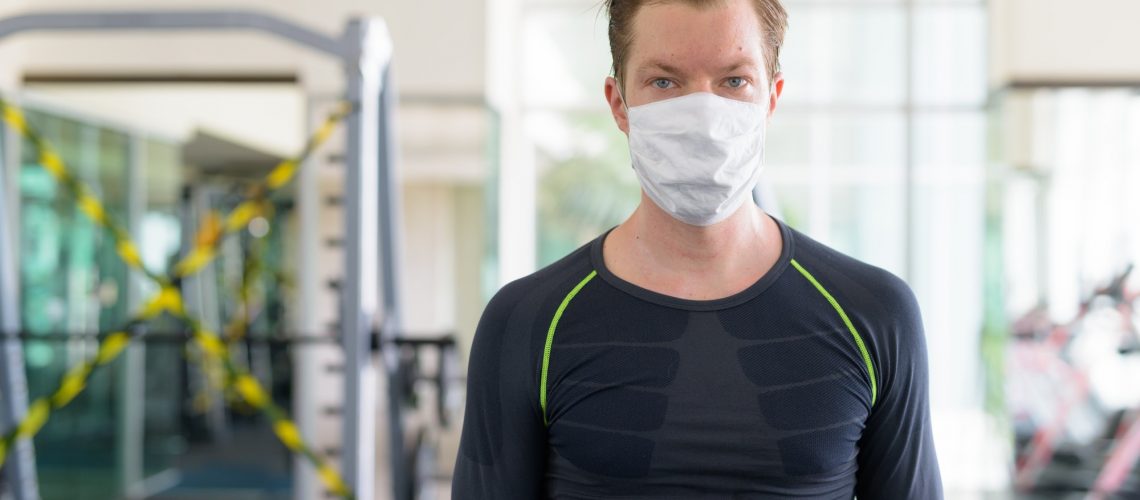 Young man with mask for protection from corona virus outbreak at gym during corona virus covid-19